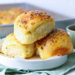 Close up of three sourdough cheese and garlic rolls on a small plate.