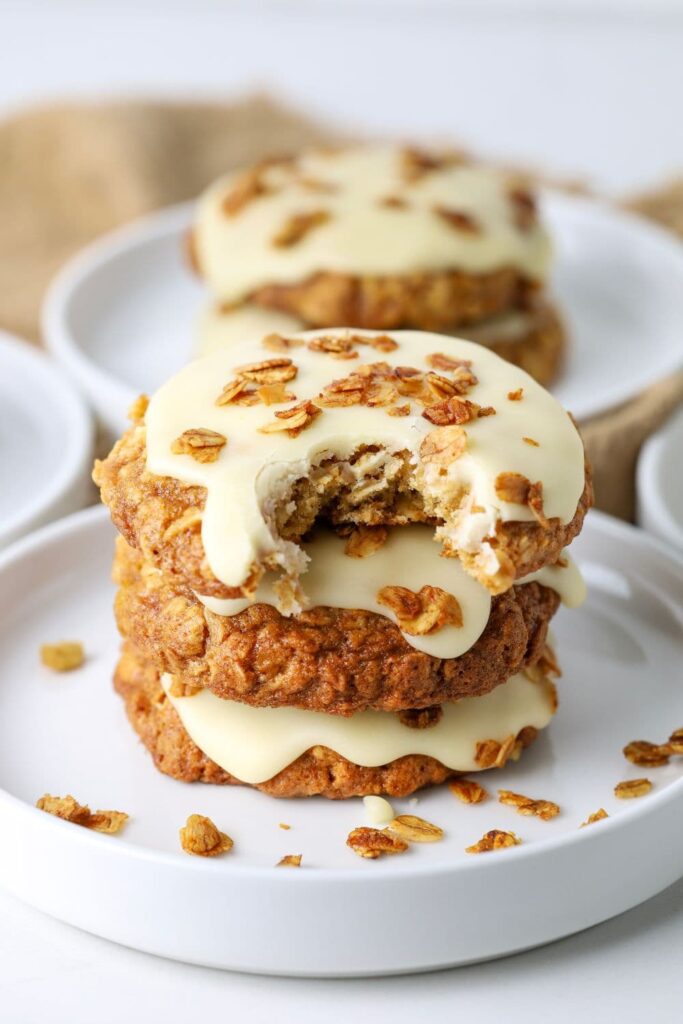 Three sourdough honey oat cookies stacked on a plate with a bite taken out of the top cookie.