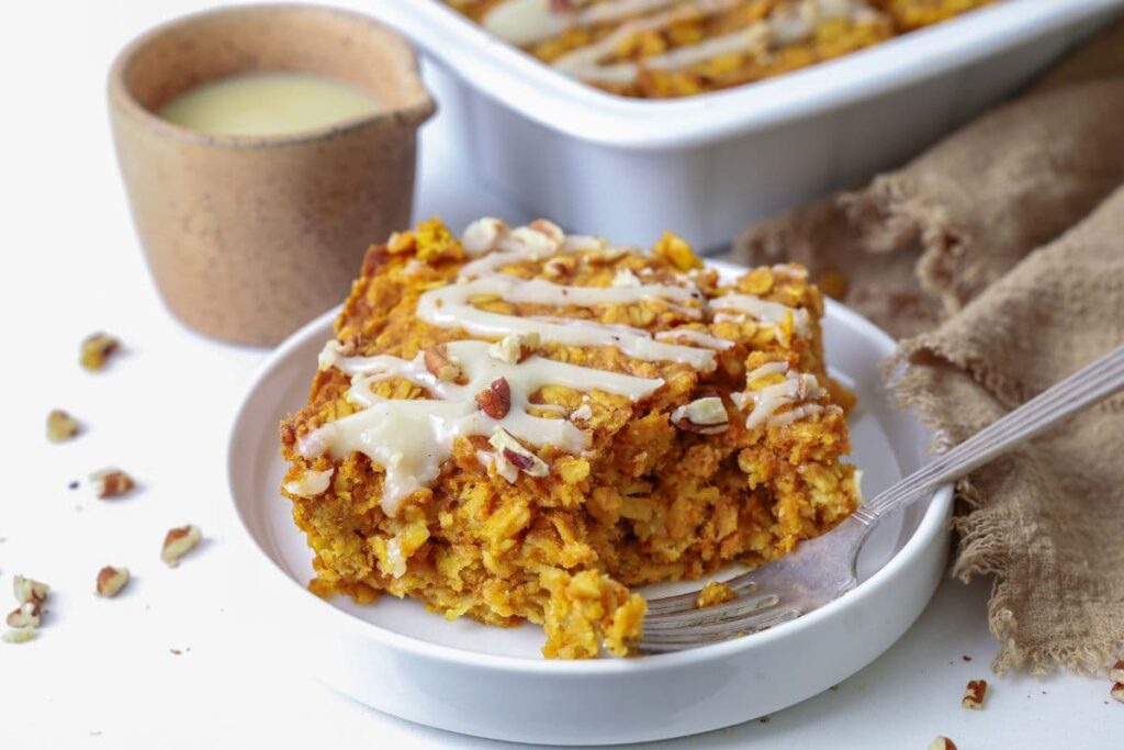 Slice of sourdough pumpkin pie baked oatmeal on a plate with a fork and a bite taken out.