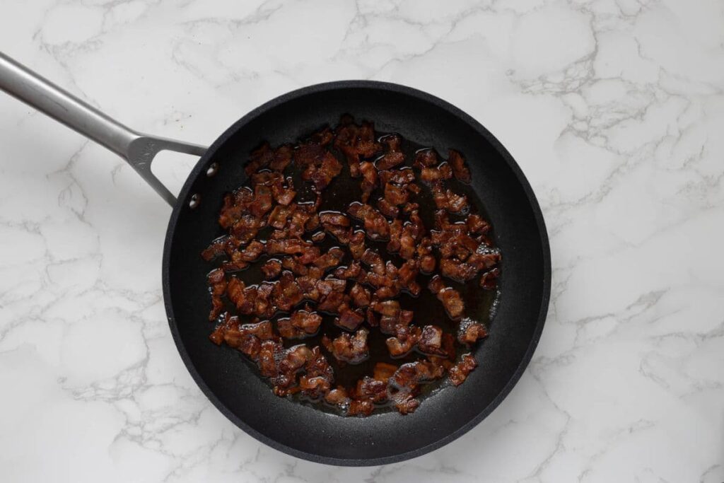 Cooking bacon in a pan to make bacon jam.