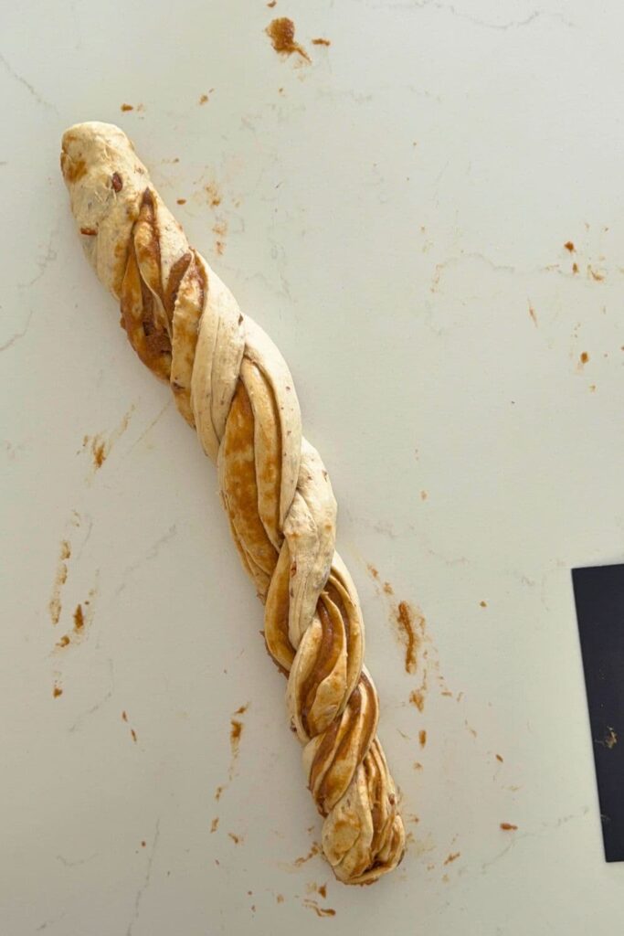 Making a rope like dough by twisting cut pieces of dough for a sourdough maple pecan twist loaf.