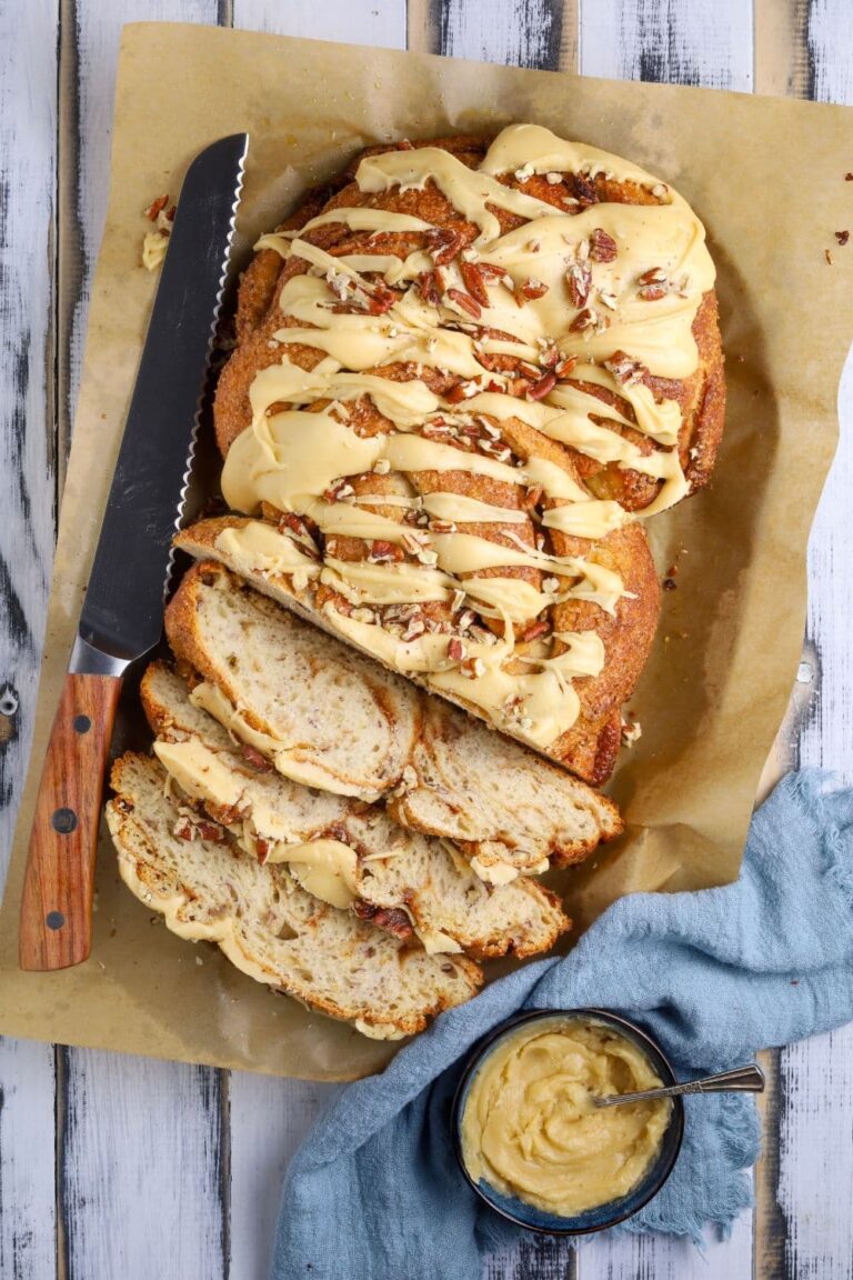 An overhead view of a sourdough maple pecan twist loaf with glaze topping and three slices sliced to show inside texture.