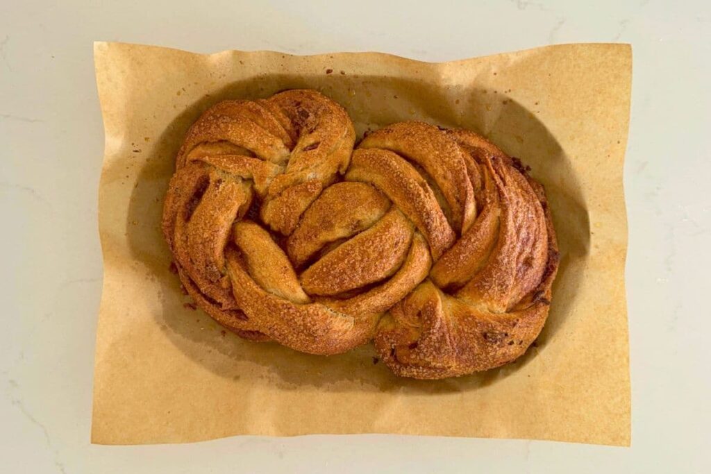 A fresh baked sourdough maple pecan twist loaf on parchment paper before any glaze topping.