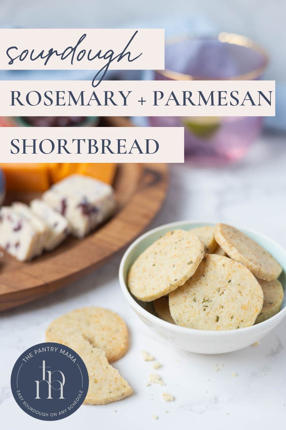 Sourdough discard rosemary and parmesan shortbread in a bowl with a cheese board in background and text overlay on the image for a Pinterest Pin.