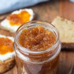A jar of carrot cake jam on a serving platter with toast and text overlay for a Pinterest image.